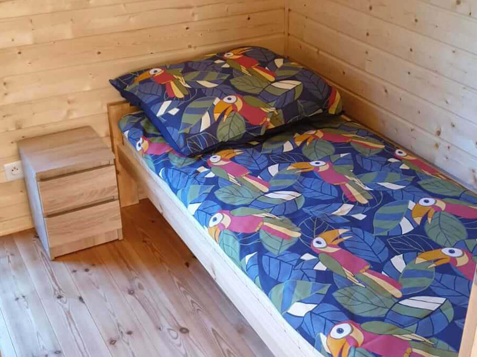 podwójne łóżko na tle drewnianej ściany
